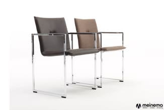 Drie moderne stoelen met chromen frame en armleuningen. Linksstoel zwart leer, middelste stoel zwart leer, rechterstoel beige