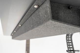 Grijze akoestische panelen aan plafond gemonteerd met zichtbare bevestigingspunten en spotverlichting.