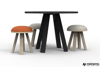 Ronde tafel met zwart blad en zwarte poten, omgeven door drie krukken met licht hout en gekleurde stoffen zittingen (oranje,