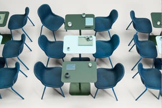 Bovenaanzicht vergadertafels in groen en wit met blauwe stoelen, laptops en kopjes gerangschikt in vergaderzetting.
