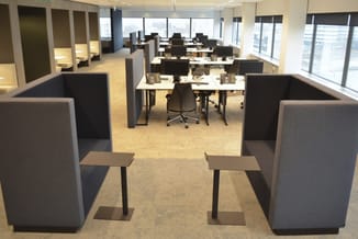 Modern kantoor met grijze akoestische schermen, werkplekken met tafels en bureaustoelen, grote ramen, hoge plafond met verlic
