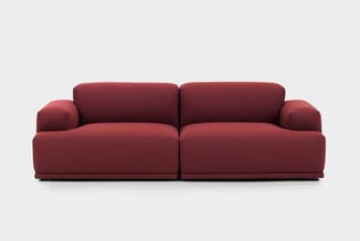 Rode modulaire bank met twee zitdelen, afgeronde armleuningen en donkere voetlijst tegen neutrale achtergrond.