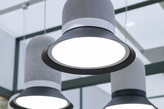 Hanglampen met grijze cilindervormige kap en zwarte ring, witte LED-schijven, in modern kantoorinterieur met glassscheiding.