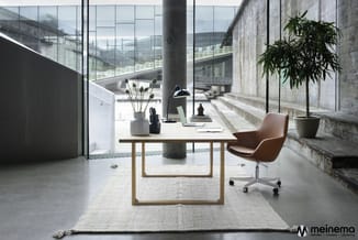 Modern kantoor met houten bureau, cognackleurige bureaustoel, potplanten en glazen ramen met uitzicht op stadslandschap.