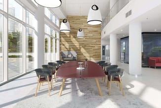 Moderne vergaderruimte met ronde bordeauxrode tafel, zwarte stoelen met houten poten, hangende witte pendellampen, houten wan