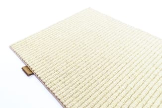 Crème-witte textielmat met geribbeld patroon en houten handgreep aan zijkant.