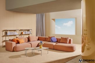 Modern woonkamer met modulaire zitbank in terracotta, grijze gordijnen, lage salontafel, houten boekenkasten en groot raam me