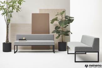Grijze zitbanken met zwart metalen onderstel, zwarte plantenpotten met groen, beige wandpanelen, bruine achterwand. Meinema-l