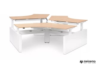 Drie elektrisch verstelbare bureaus met licht houten blad en witte onderstel in L-vorm configuratie.