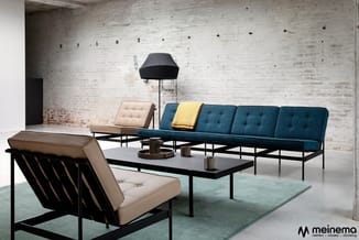 Moderne loungeset met beige en blauwe fauteuils, blauwe sofa met gele kussen, zwarte salontafel en staande lamp in industriee