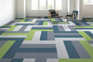 Moderne kantoorruimte met groen-blauw grafisch tapijt, twee zwarte houten stoelen en klein tafelblad bij raam.