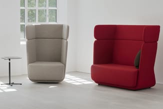 Twee lounge fauteuils in minimalistische ruimte: grijsbeige en bordeauxrood, met afgeronde vormen, naast glazen bijzettafel e
