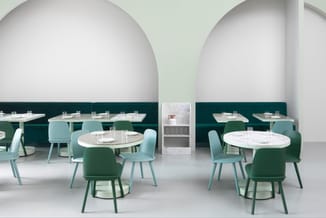 Modern restaurant interieur met ronde witte tafels, licht- en donkergroene stoelen, donkergroene wandafwerking en witte gewel