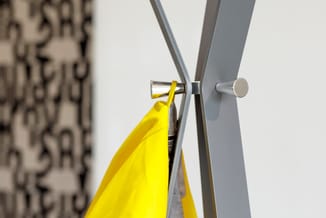 Gele werkplek scheidingswand met grijs aluminium frame en zilveren klemmen tegen witte muur.