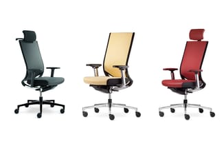 Drie ergonomische bureaustolen met wielen: zwarte mesh, beige/crème stof, en rode stof uitvoering, elk met armsteunen en hoof
