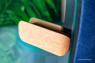 Glazen wand met houten handgreep en donkere afwerkingsprofiel, tegen blauwe akoestische stof.