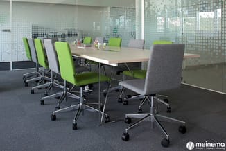 Moderne vergaderruimte met rechthoekige tafel, groene en grijze bureaustoelen op wielen, glazen wanden met rasterpatroon, gri