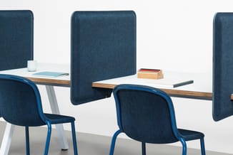Twee blauwe stoelen met ergonomische rugleuning aan een houten bureau met blauwe akoestische scheidingspanelen en werkaccesso