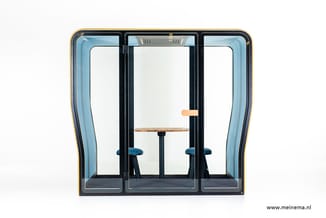 Akoestische telefooncel met zwart frame, blauwe zijpanelen, werkblad en twee blauwe stoelen, openslaande deur met houten hand