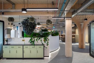 Modern kantoor met groene kastenwand, betonnen keukeneiland met planten, hangende bollampen, houten zuilen en archiefkasten m