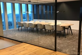 Moderne vergaderruimte met witte vergadertafel, beige stoelen, glazen wanden en panoramisch uitzicht op stadsskyline.