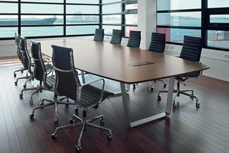 Moderne vergadertafel met zwarte bureaustoel en raamzicht op water, donker houten vloer.