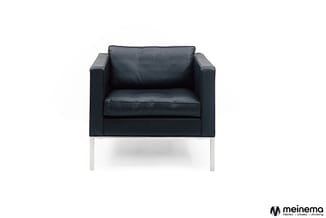 Zwarte leren fauteuil met vierkante vorm en zilverkleurige metalen poten, frontaal gefotografeerd tegen witte achtergrond.