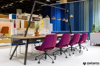 Moderne vergaderruimte met houten tafel, paarse bureaukstoelen op wielen, blauwe verticale lamellen, hangende messing verlich