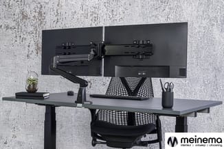 Zwart bureau met elektrisch verstelbaar blad, twee monitoren op zwarte monitorarm, zwarte ergonomische bureaustoel, grijze ac