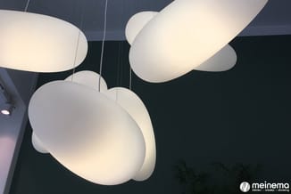Witte hangende designlampen met organische vormen tegen donker plafond in moderne kantoorruimte met plant.