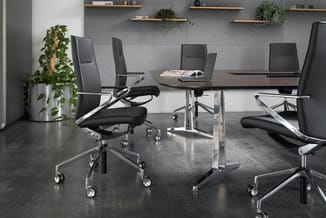 Modern kantoor met zwarte ergonomische bureaustoelen met chromen frame, zwarte vergadertafel, grijze muur met houten wandplan