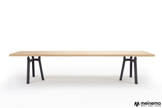 Lange houten vergadertafel met lichte houttint op zwart metalen tresselonderstel, zijkant.