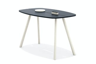 Ovale bureau met zwart blad en vier natuurlijk gelakte houten poten. Op het blad liggen een wit bord en een donker object.