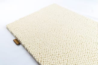 Witte structuurstof met bolletjestextuur op een licht gestoffeerd paneel met houten handvat.