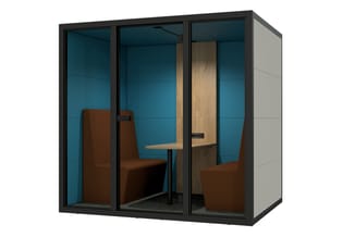 Akoestische belcel met zwart aluminium frame, blauwe wanden, houten deur, bruin zitbank en tafel tegen teal achtergrond.