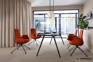 Vergaderruimte met zwarte tafel, vier rode velvet stoelen op zwart metalen onderstel, hanglamp, beige gordijnen, grote ramen