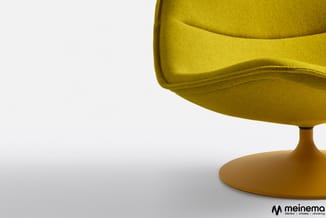 Gele loungefauteuil met ovale zitting en goudkleurige voetsteun op wit oppervlak, meinema-logo zichtbaar.
