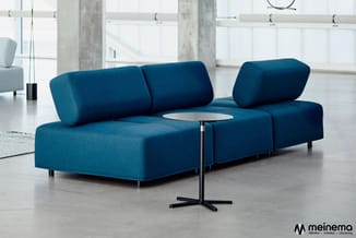 Blauwe modulaire zitgroep met cilindervormige rugleuningen in moderne kantoorruimte met betonnen zuilen, wit tafelblad en zwa