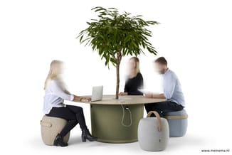 Drie personen zitten rond een ronde groene tafel met plant. Zitpoefs in beige en grijs, laptop op tafel, witte achtergrond.