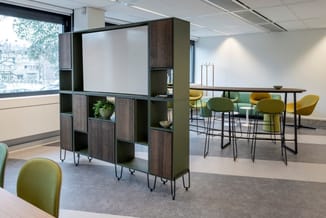 Modern kantoor met groen-gele barkrukken, houten kastensysteem met whiteboard, hoge tafel en grote ramen met stadsuitzicht.