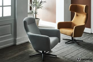 Twee moderne fauteuils in een lichte ruimte: grijze draaibare zetel vooraan, gele/goudkleurige loungestoel op kruisvoet achte