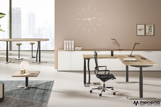 Modern kantoor met houten bureau's, zwarte bureausstoel, witte kasten, ronde tafel met barkrukken, grijze bank, wandklok en g