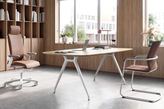 Modern kantoor met houten wandkasten, witte vergadertafel, roze bureaustoel op wielen en bruin kantoorstoel, grote ramen met