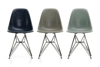 Drie modern vormgegeven stoelen met kunststof zitting in donkerblauw, grijs en groen, elk op een stalen frame met splayende p