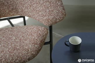 Bruine stoelen met zwarte frame rond donkerblauw tafelblad met zwarte beker, in minimalistische interieursetting.