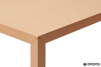 Houten tafel met licht natuurkleurig blad en donkerbruin randelement, detail van hoek en poot tegen witte achtergrond.