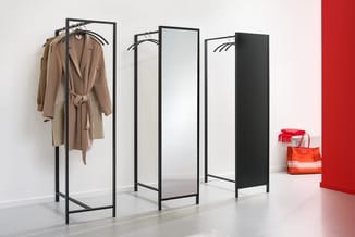 Zwart metalen garderobe met spiegelpanelen en kledingrek, beige jas hangend, rode accessoires ernaast in moderne kantoorruimt