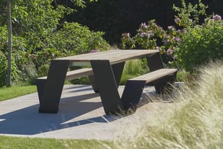 Moderne picknicktafel met zwarte trapeziumvormige poten en naturel houten zit- en tafelblad, buiten in tuinomgeving.
