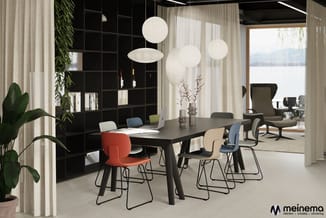Modern kantoor met zwarte vergadertafel, gekleurde stoelen (rood, wit, blauw), hangende bolverlichting, zwarte kasten, groene