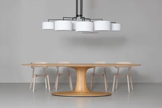 Houten vergadertafel met ovaal blad en centraal voetsteun, vier houten stoelen met grijze bekleding, hangende design-plafondl
